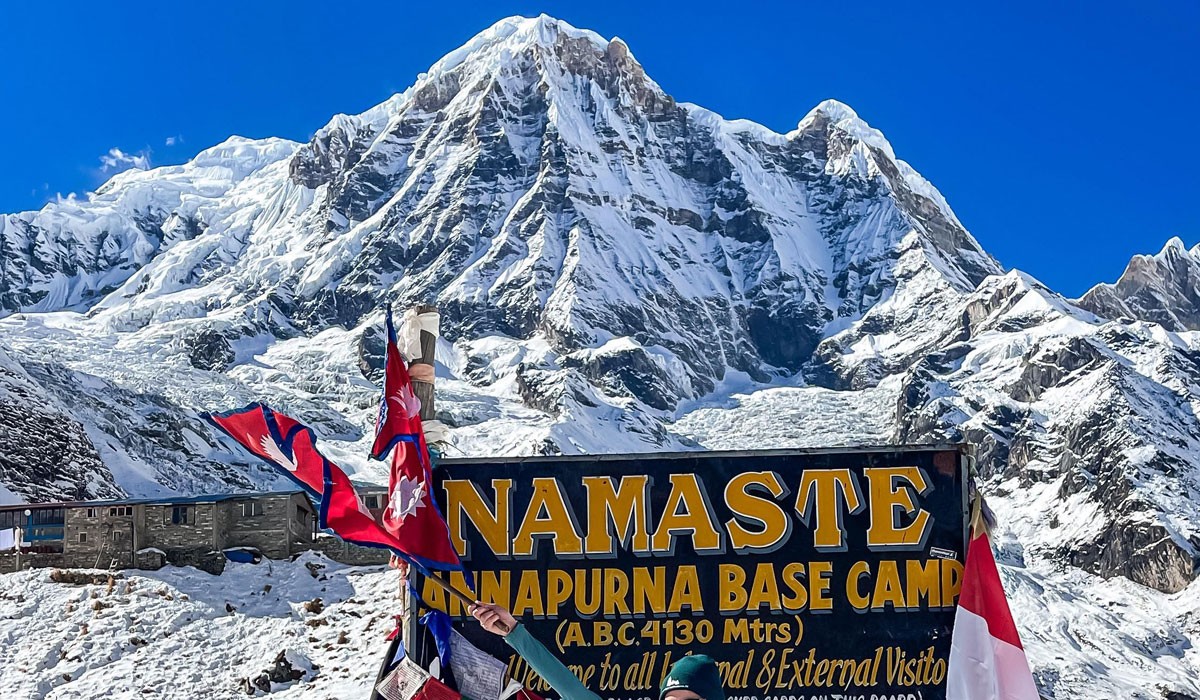 Trekker enjoying the panoramic view of Annapurna peaks from a high mountain trail surrounded by forests and valleys.