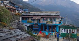 Traditional tea house in the Manaslu region with stone walls and tin roof, surrounded by mountains and offering shelter for trekkers.